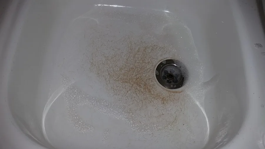 Waschbecken mit Haaren und Ablagerungen vor der Reinigung