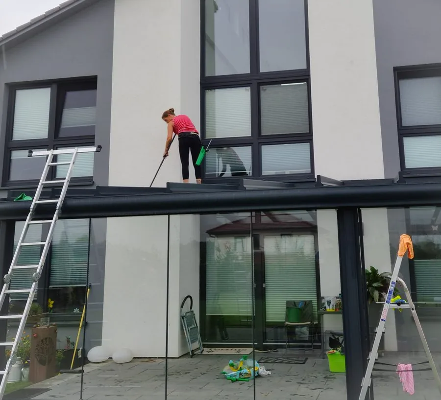 Mitarbeiterin des Reinigungsservice Nicolai bei der Glasreinigung an einem Vordach